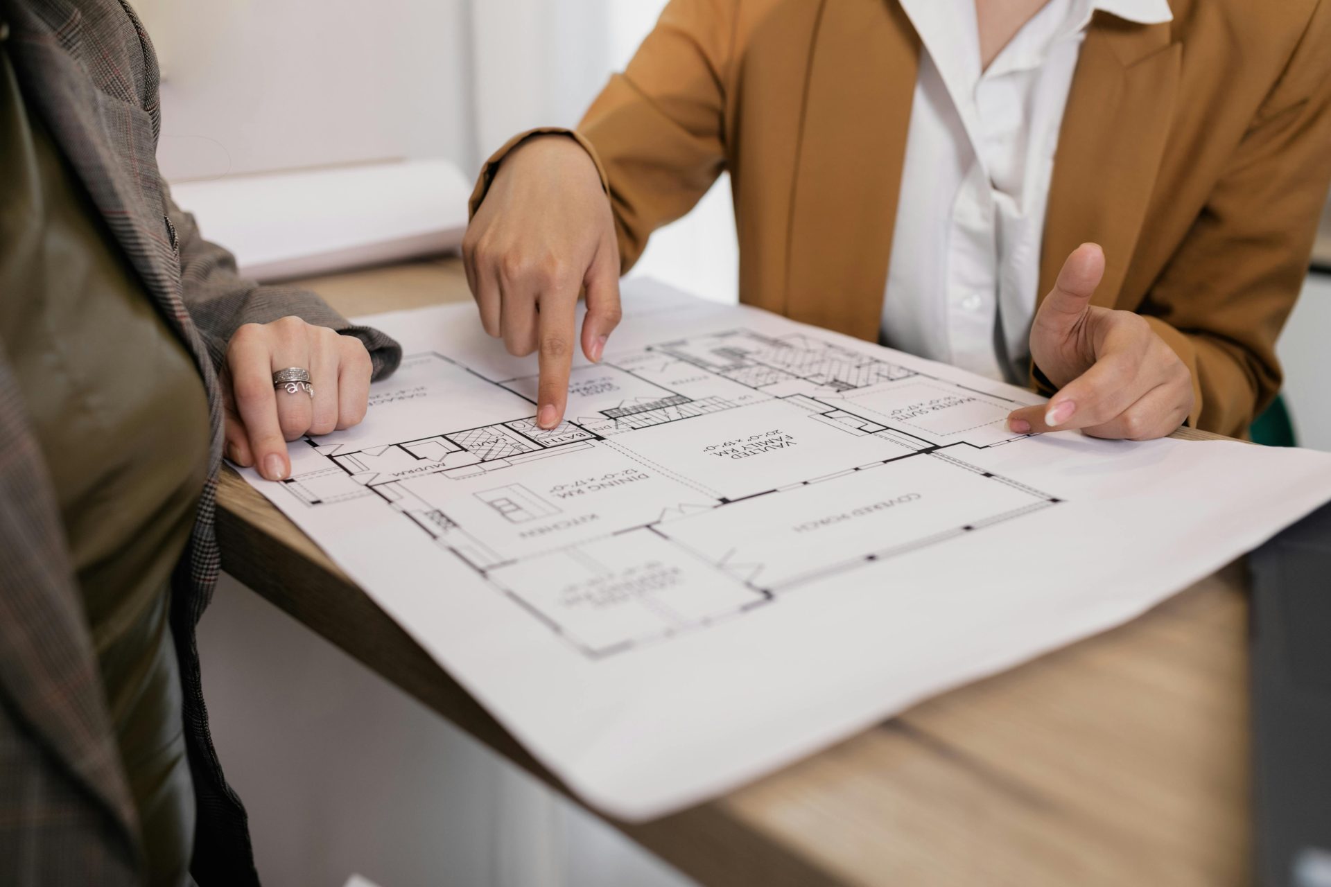 Zwei Fachleute prüfen Architekturpläne und konzentrieren sich dabei auf Grundriss und Designdetails.